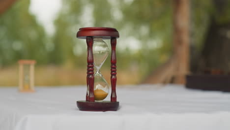 wooden hourglasses with sand stand on table in yard