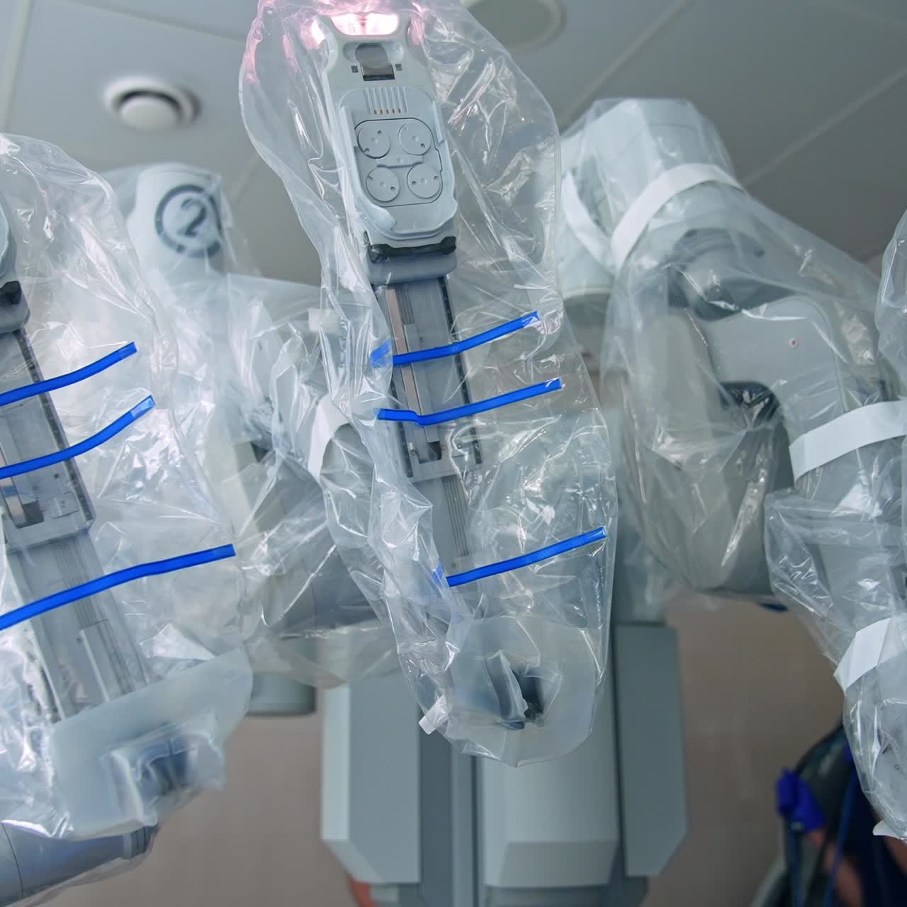 Close look at the robotic arms of advanced equipment in surgery room. Circle movement around Da Vinci robot covered with plastic