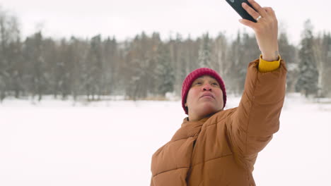 vista frontal del hombre latino en el bosque de invierno haciendo un selfie