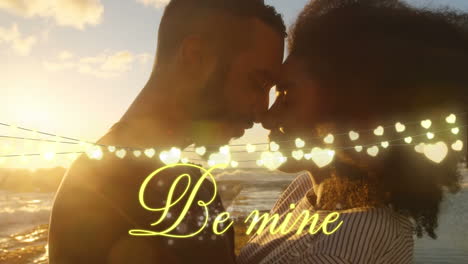 couple in love on the beach with be mine written in golden letters