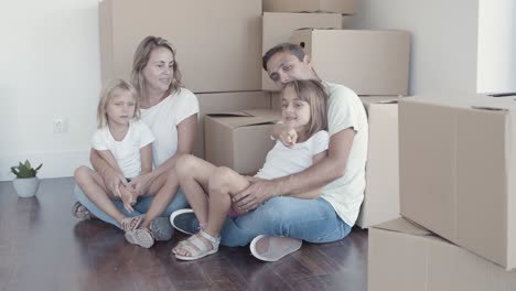 padres y dos hijas sentadas en el suelo cerca de las cajas
