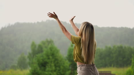 woman with loose hair reaches hands to catch rain drops