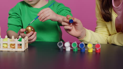 playful children painting eggs using watercolor and brushes