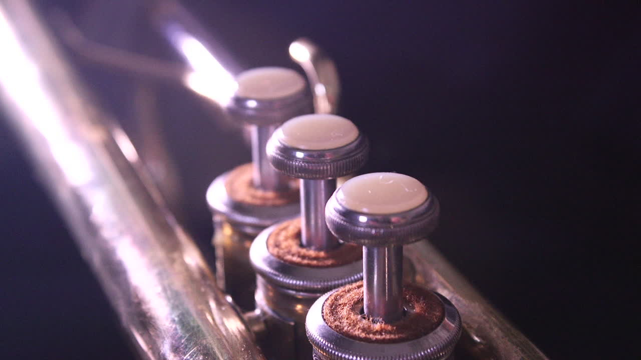 Lights shining on the valves of a brass trumpet.