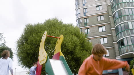 bottom view of a little girl with down syndrome playing with other kids in the park on a windy day. they are getting on slide