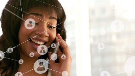 Animation of network of profile icons against african american woman talking on smartphone at office