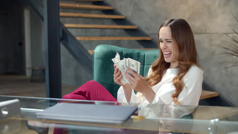 joyful business woman counting money in office