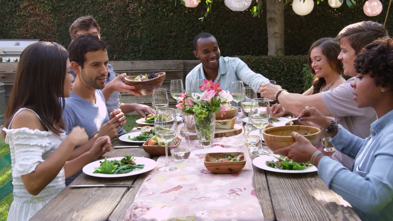 Amis mangeant et buvant à une table de fête en plein air, filmé en R3D