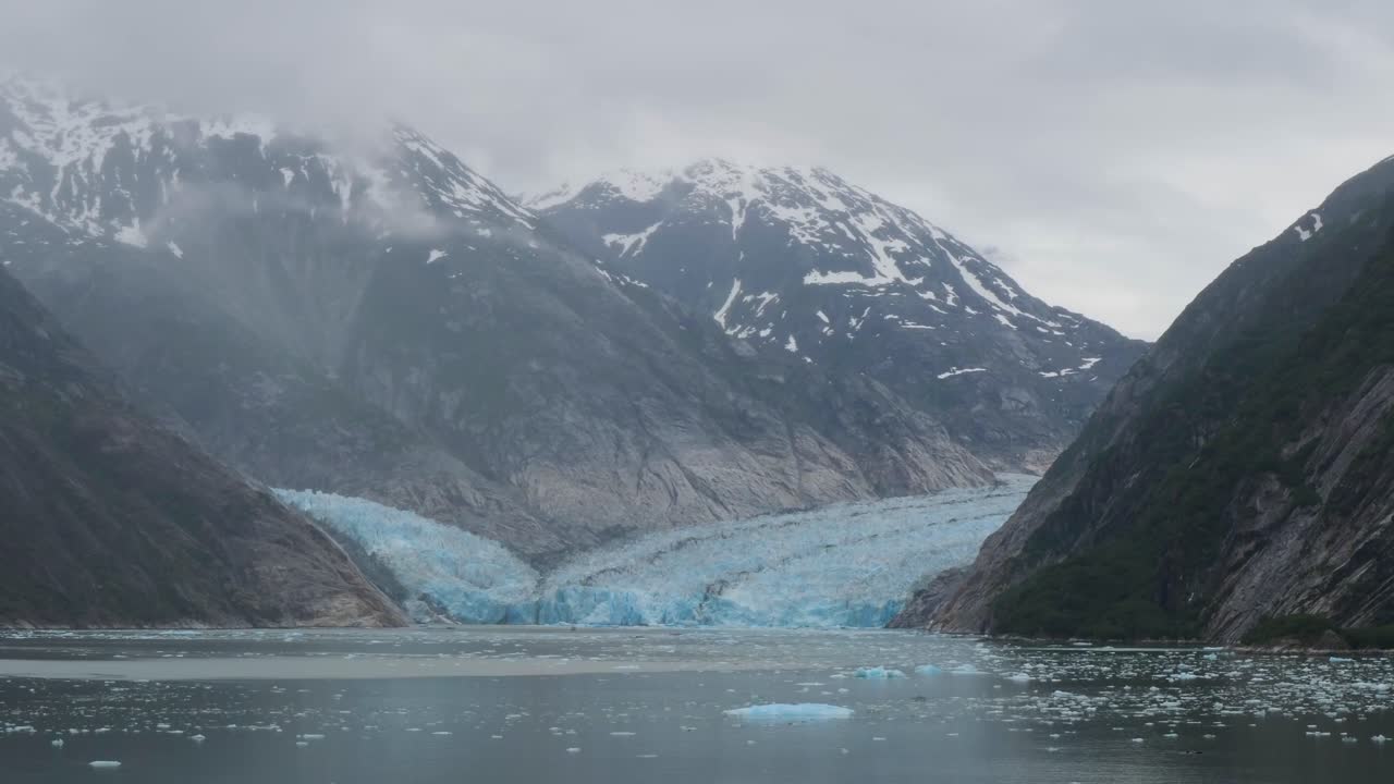 Snow-capped mountains covered by dense fog at Dawes Glacier, Endicott Arm fjord, Alaska.