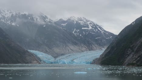 snow-capped mountains covered by dense fog at dawes glacier, endicott arm fjord, alaska.