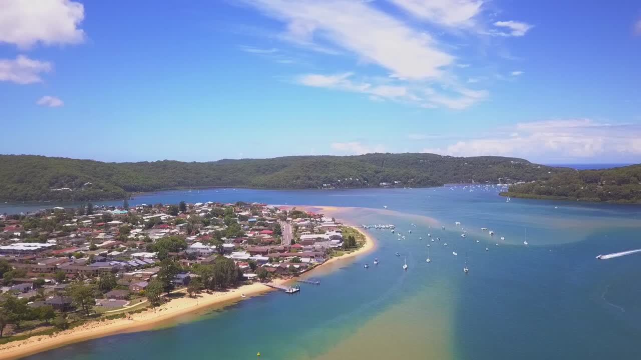 Beautiful blue water beach and waterfront houses with amazing natural ocean view. Elevating shot revealing speed boat crossing the shore in a sunny day.