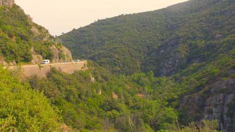 a wide scenic view of rolling hills, forest and distant mountain ranges under soft summer light