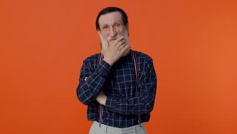 Senior-smiling-old-man-with-gray-haired-looking-at-camera,-fixing-beard-posing-on-orange-background