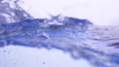 Wasserspritzeroberfläche,-Die-Den-Rahmen-Mit-Zeitlupe-Füllt,-Der-Wassertropfen-Und-Winkende-Flüssigkeit-Mit-Einer-Luftblase-Auf-Weißem-Hintergrund