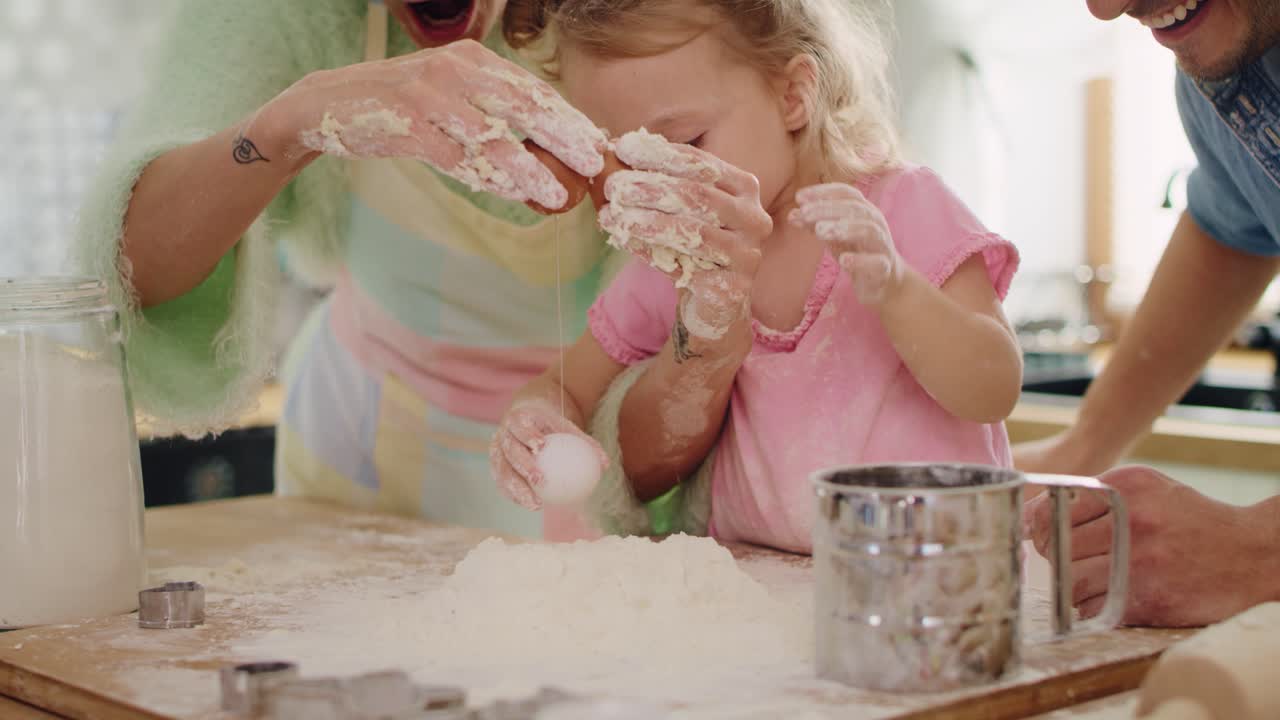 Handheld view of little girl making cookies with parents