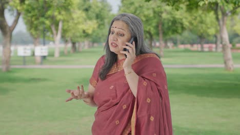 angry indian old woman shouting on phone in park