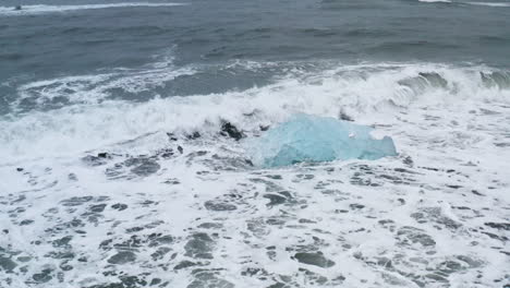 stunning drone shot of waves breaking on beautiful ice rocks at diamond beach in iceland