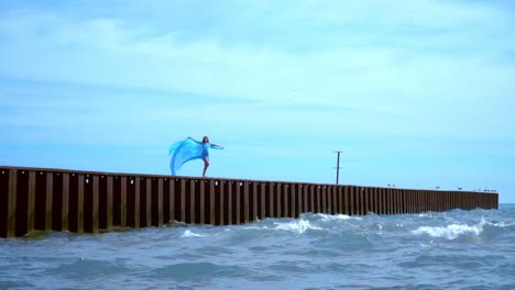 woman in flying dress on sea pier. woman flying in wind. romantic concept