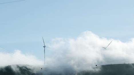 Weiße-Wolken-Rollen-An-üppigen-Bergen-Mit-Windkraftanlagen-Während-Eines-Dunstigen-Morgens-In-Serra-De-Aire-E-Candeeiros,-Leiria-Portugal