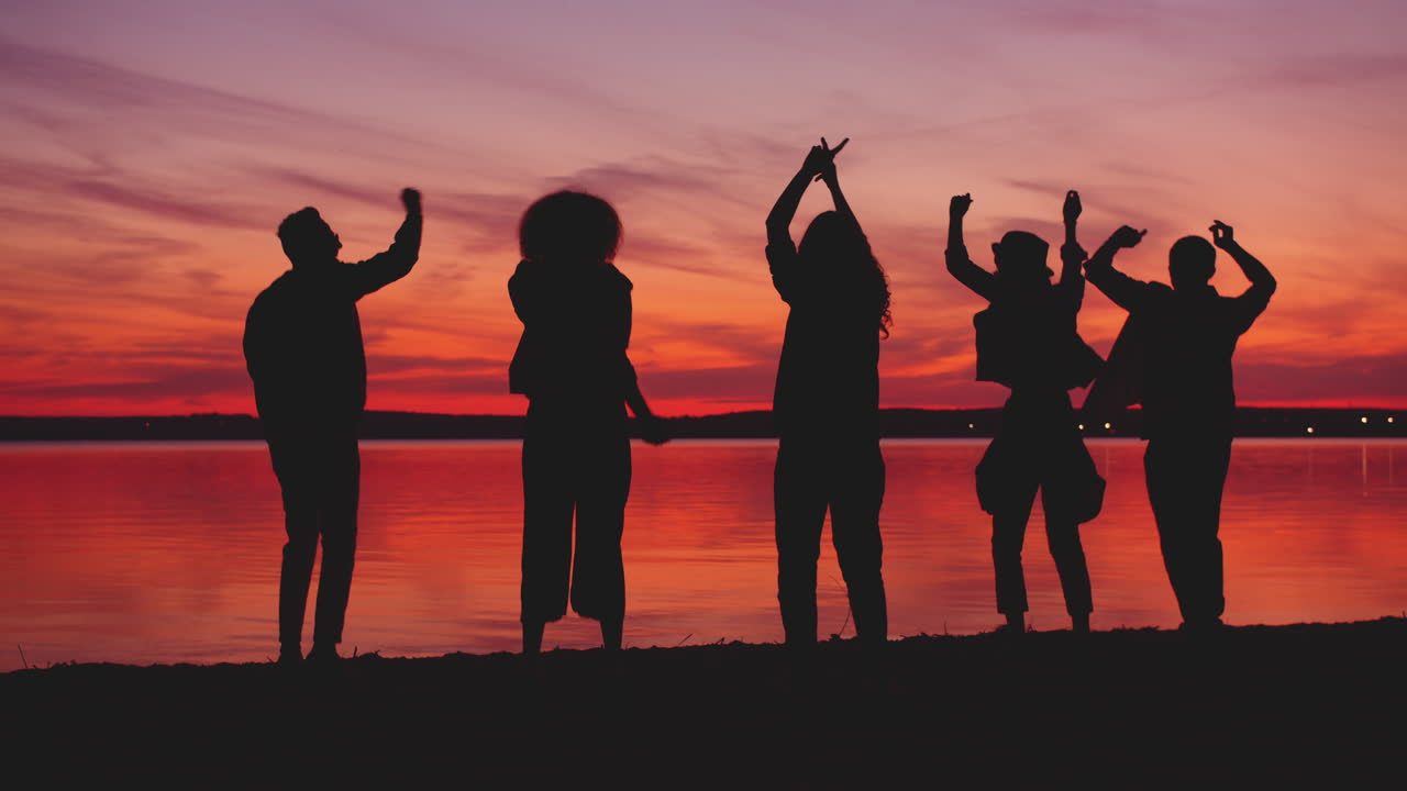 해변에서 해가 지면 친구들이 춤을 춘다