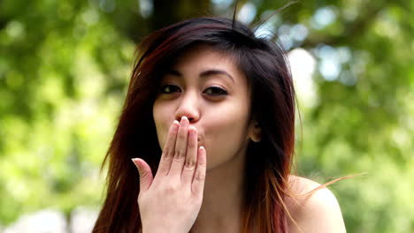 Pretty-asian-girl-blowing-kiss-to-the-camera-outside