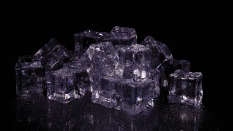 montón de cubitos de hielo con un tinte púrpura girando sobre un fondo negro, disparo de estudio estático hacia abajo