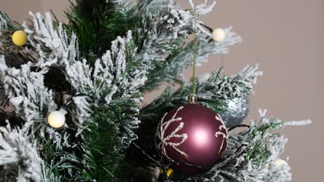 la mano de la mujer puso la decoración navideña en la rama artificial del árbol de navidad