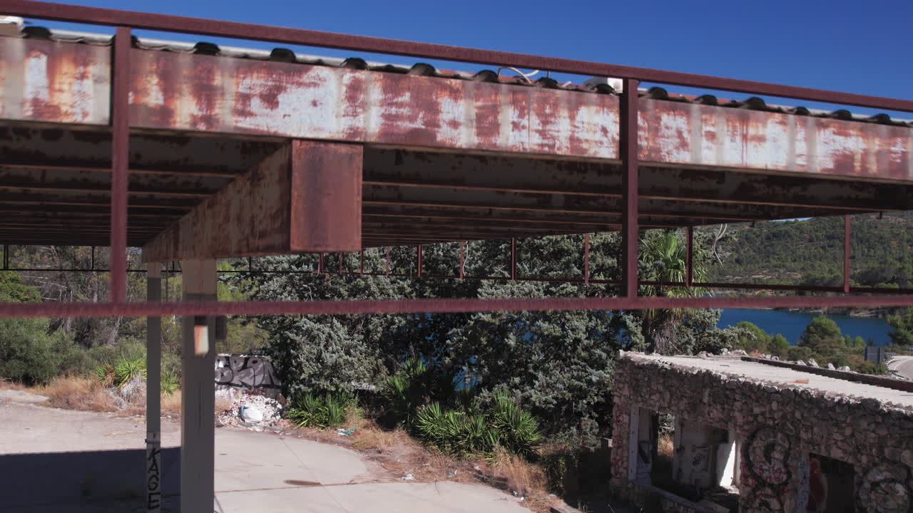 Aerial moving shot of an abandoned gas station, flying over it to reveal the Embalse de Entrepeñas reservoir, Spain