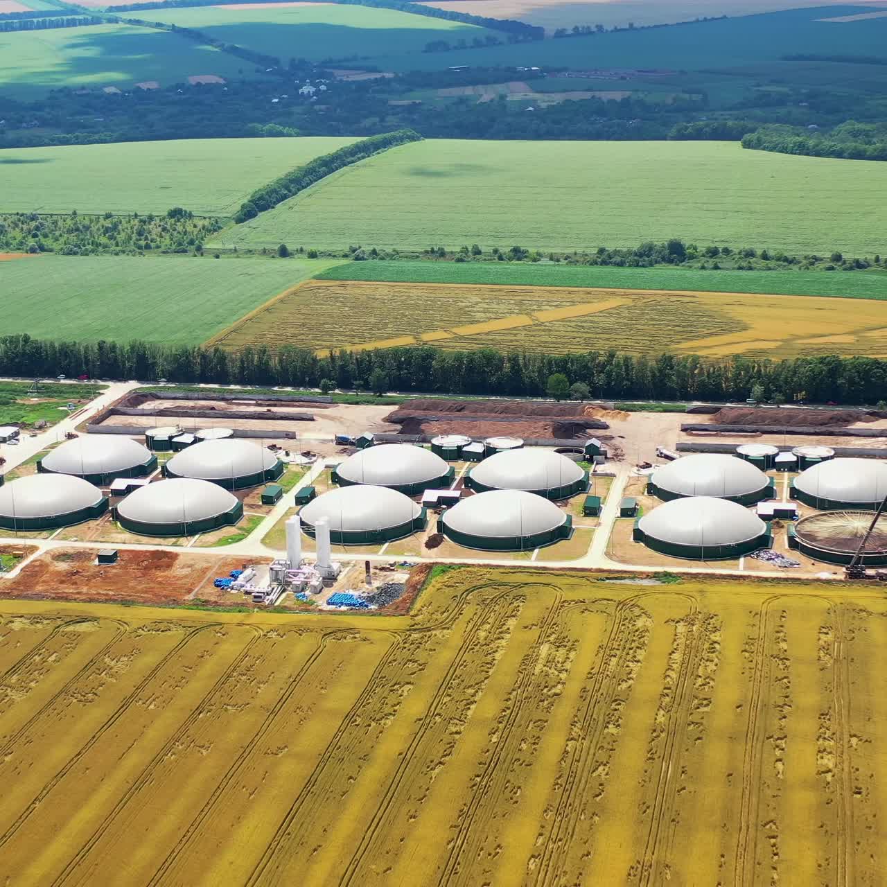 New factory among beautiful nature. Plant for biogas production on fields. Modern complex is equipped with its own biogas. Aerial view