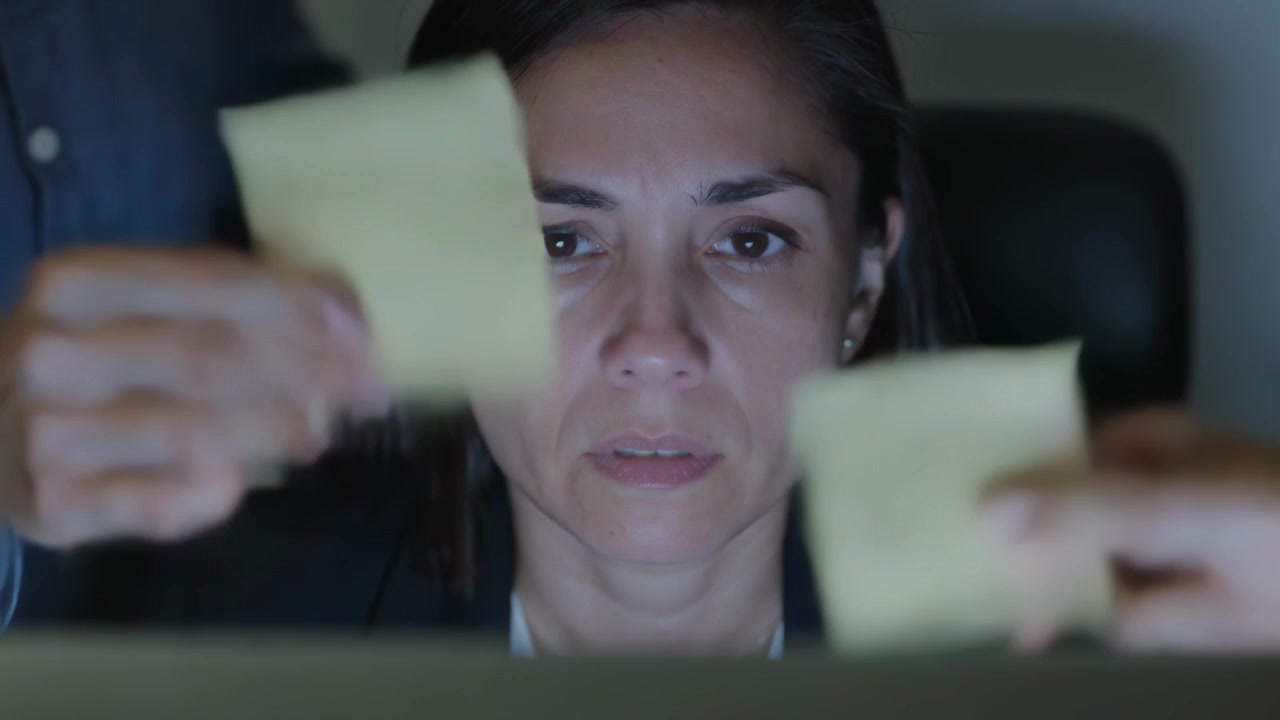 Moving colleague hands placing yellow sticky notes over woman in dark blazer at desk, distracting