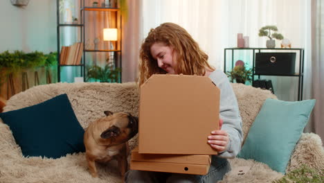 young woman ordering pizza on smartphone at home with smiling pug dog waiting for delicious food