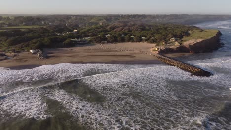 Aerial-shot-of-beautiful-coastline-of-Luna-Roja-with-sandy-beach-and-reaching-waves-of-Atlantic-Ocean---Chapadmalal,-Argentina