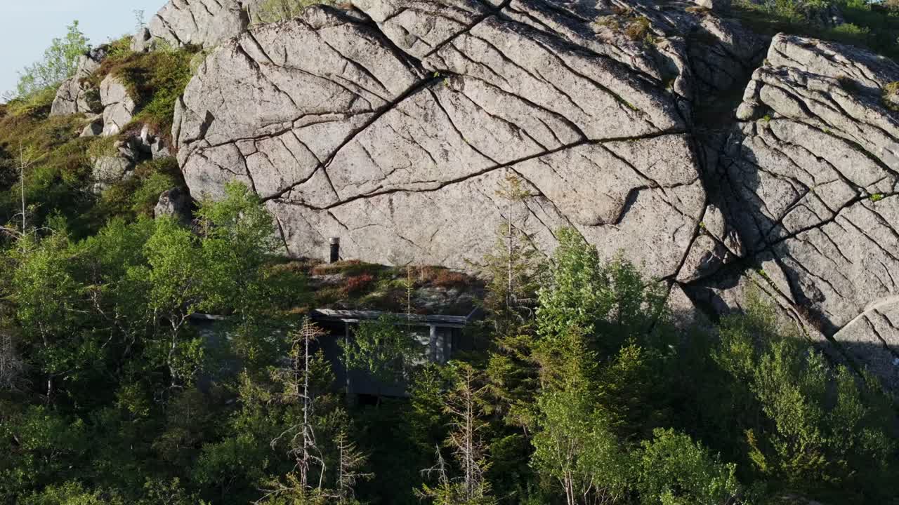 hesttjønna, indre fosen, trondelag, noruega - cabañas de madera que descansan en la base de una montaña rocosa - toma de ángulo alto
