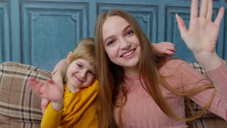 Child-kid-daughter-with-mother,-embracing,-waving-hands-to-camera-doing-hello-welcome-or-bye-gesture