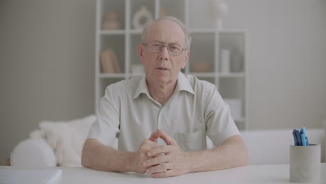 elderly blogger is talking and looking at camera portrait of man at home online communication and video chat