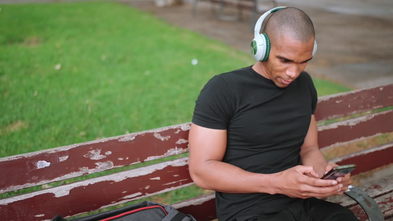 Concentrated man listening typing on phone on bench