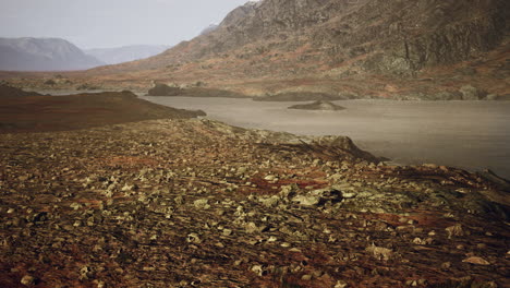 Clear-river-with-rocks-leads-towards-mountains-lit-by-sunset