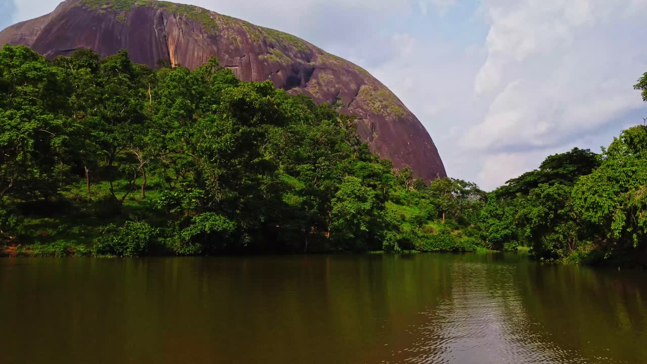 Amazing aerial of a beautiful river while the camera slowly tilts up to Aso Rock in Abuja, Nigeria in Africa.