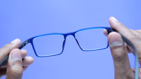 close up of man hand holding blue  eyeglass,