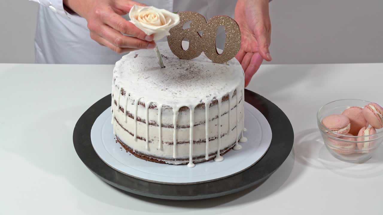 chef terminando un ensamblaje de pastel de cumpleaños colocando una rosa como decoración decoración final. celebrando sesenta años de edad.