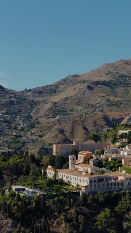 vertical aerial drone shot flying towards the ancient town of taormina in sicily. spectacular view of italian village on top of the mountains. most popular travel destination in sicily.