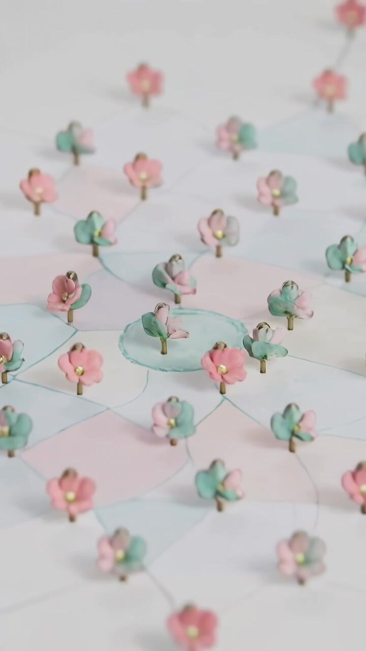 Vertical video: Panning camera revealing pastel flowers with gold dots on paper, showing paint wash