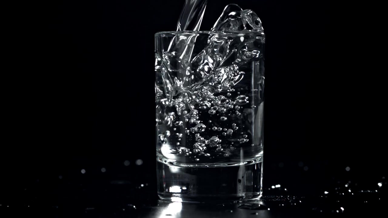 Klart vand hældes ned i et glas i slowmotion