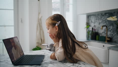 Interested-kid-calling-laptop-kitchen-interior-closeup.-Distance-communication