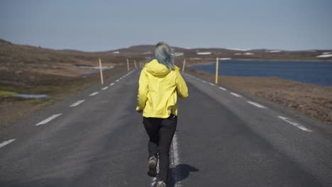 this was taken at a higher frame rate and has been converted to a slow motion video clip.  lady running on the middle of a two way road in iceland. very dramatic.