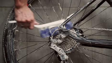 Crop-man-cleaning-gear-cassette-of-bike-wheel