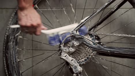 crop man cleaning gear cassette of bike wheel