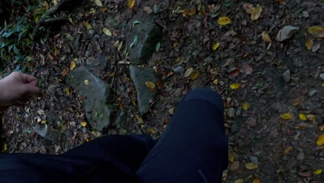 Unique-point-of-view-of-legs-and-feet-of-hiker-walking-a-wooded-and-stoney-trail