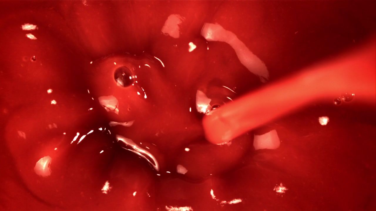 Primo piano di liquido rosso denso e vorticoso con bolle.