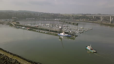 Aerial-footage-of-a-fishing-boat-returning-to-South-Queensferry-harbour-on-a-sunny-day-in-West-Lothian,-Scotland